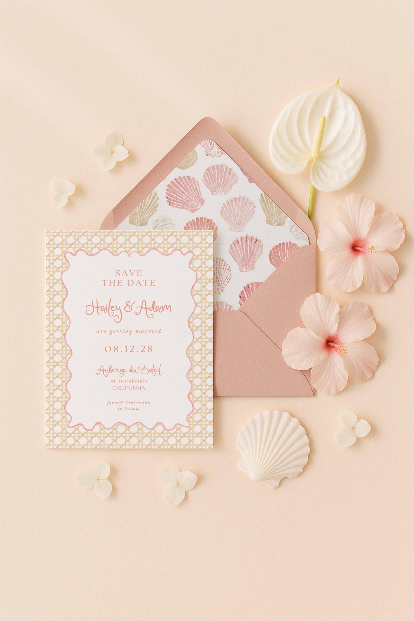 A pink and white wedding invitation card with the text "Save the Date" and "Holly & Adrien are getting married 08.12.28" is surrounded by pink flowers and shells on a peach background.