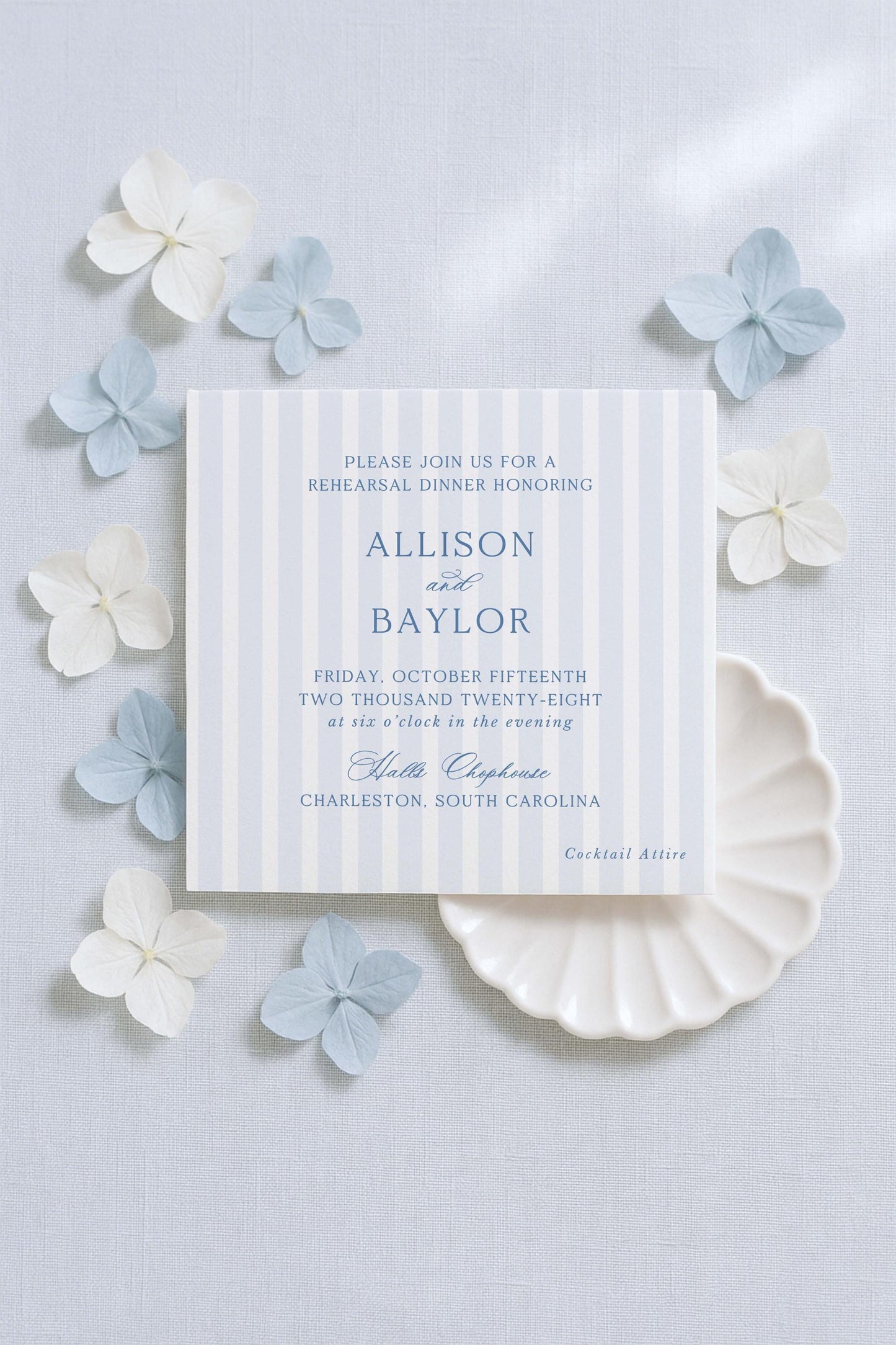 The image is a wedding invitation featuring a blue and white striped background, with delicate white and light blue flowers surrounding it.