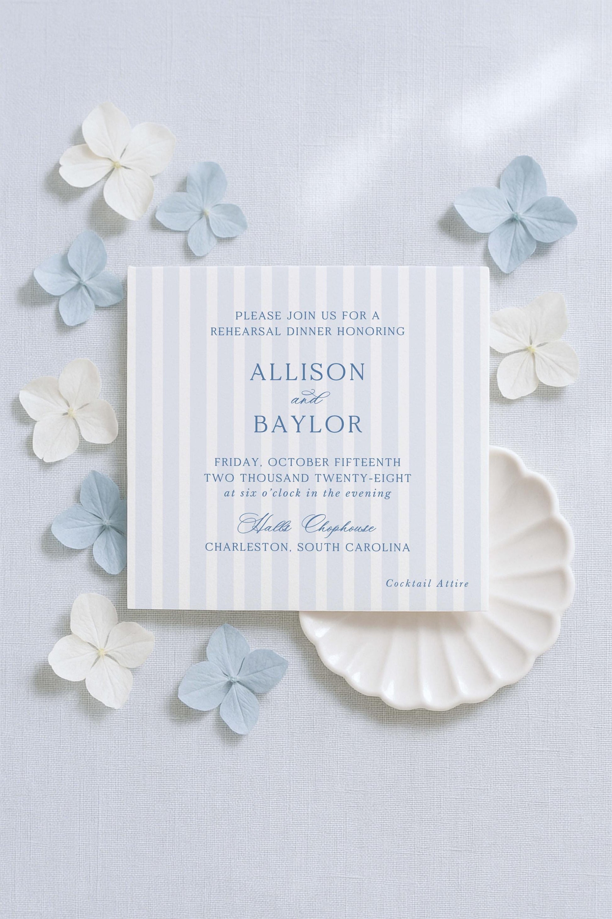 The image is a wedding invitation featuring a blue and white striped background, with delicate white and light blue flowers surrounding it.