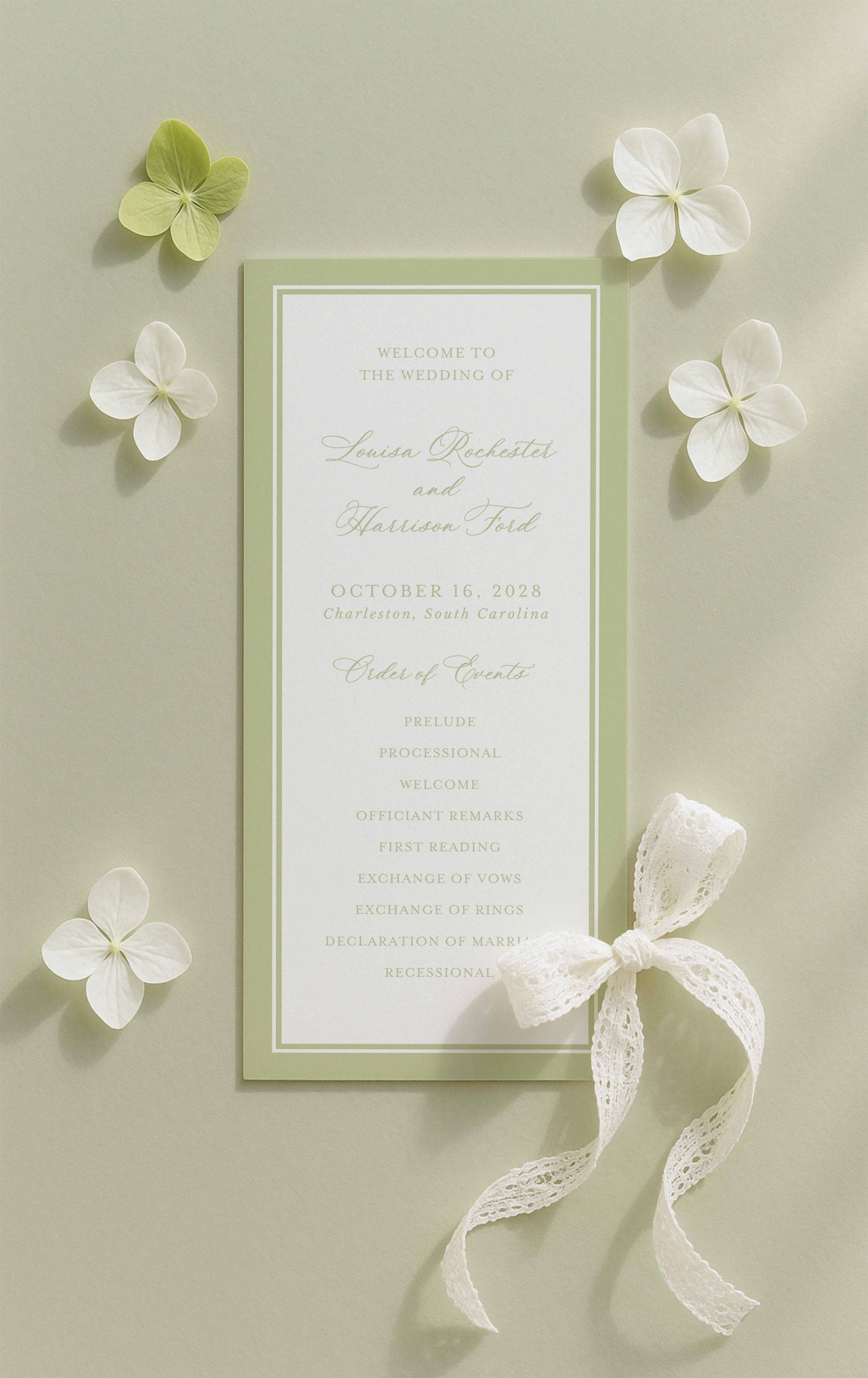 a wedding invitation card with a green and white color scheme, surrounded by white flowers and a white ribbon.