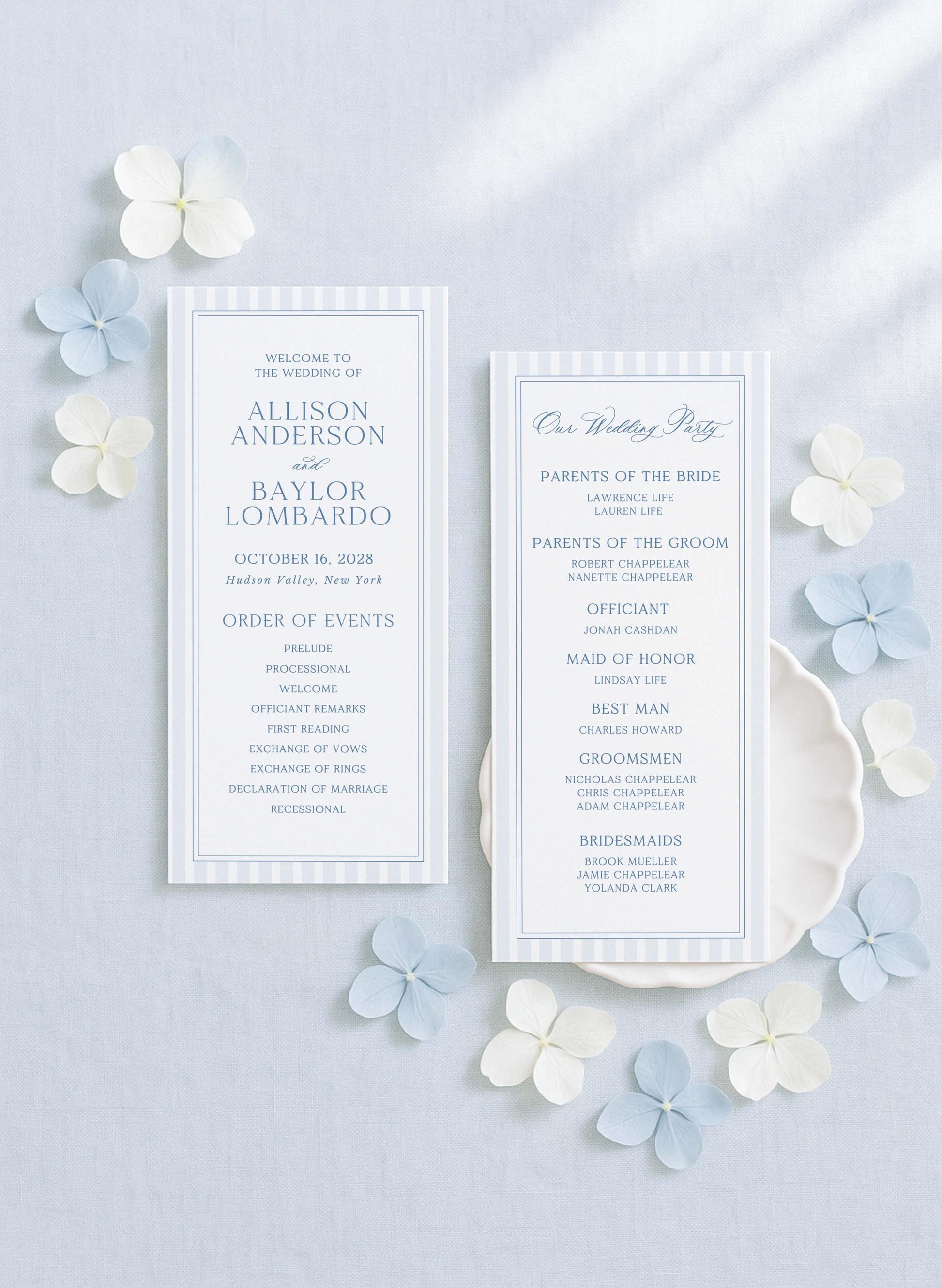two white wedding invitation cards with blue and white floral accents, placed on a light blue background.