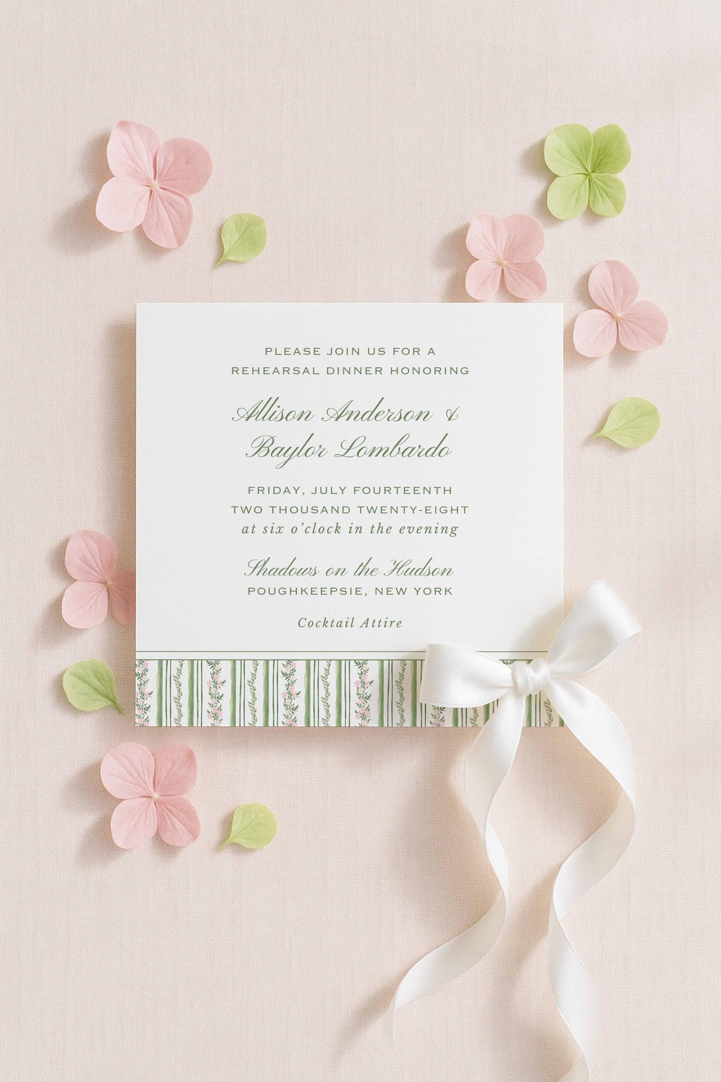 The image is a wedding invitation card with a white background, green and pink floral accents, and a white ribbon bow.