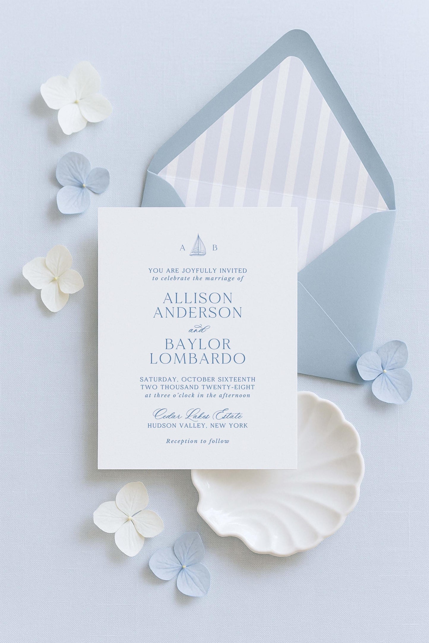 a wedding invitation card with the names Allison Anderson and Baylar Lomardo, along with details about the wedding ceremony and reception. The card is placed on a light blue background, surrounded by white and light blue flowers.