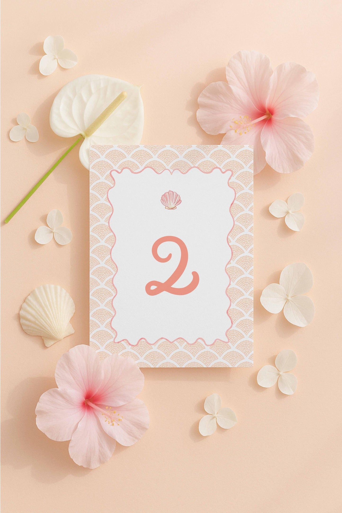 a white card with the number 2 on it, surrounded by various pink flowers and shells on a peach-colored background.