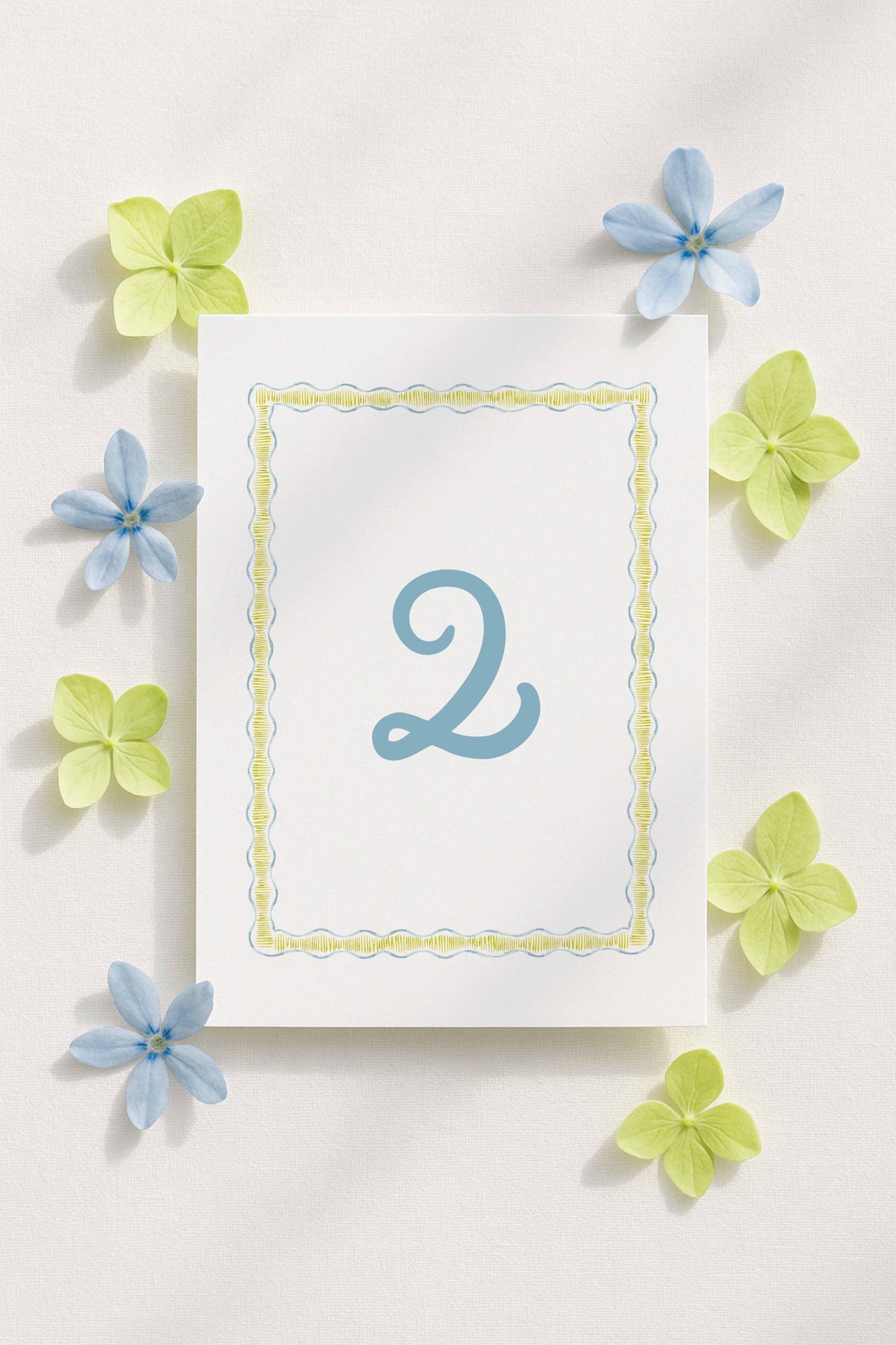 a white card with a blue number "2" in the center, surrounded by blue and green flowers.