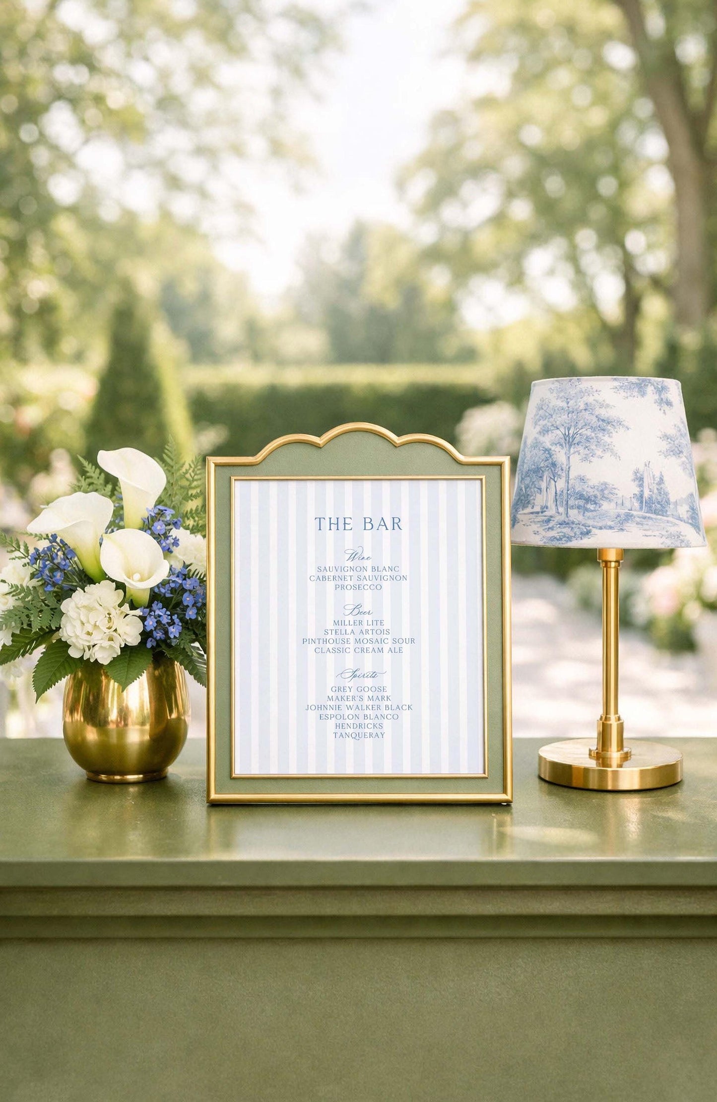 a framed menu with a decorative blue and white lamp on a table, surrounded by a vase of white and blue flowers.
