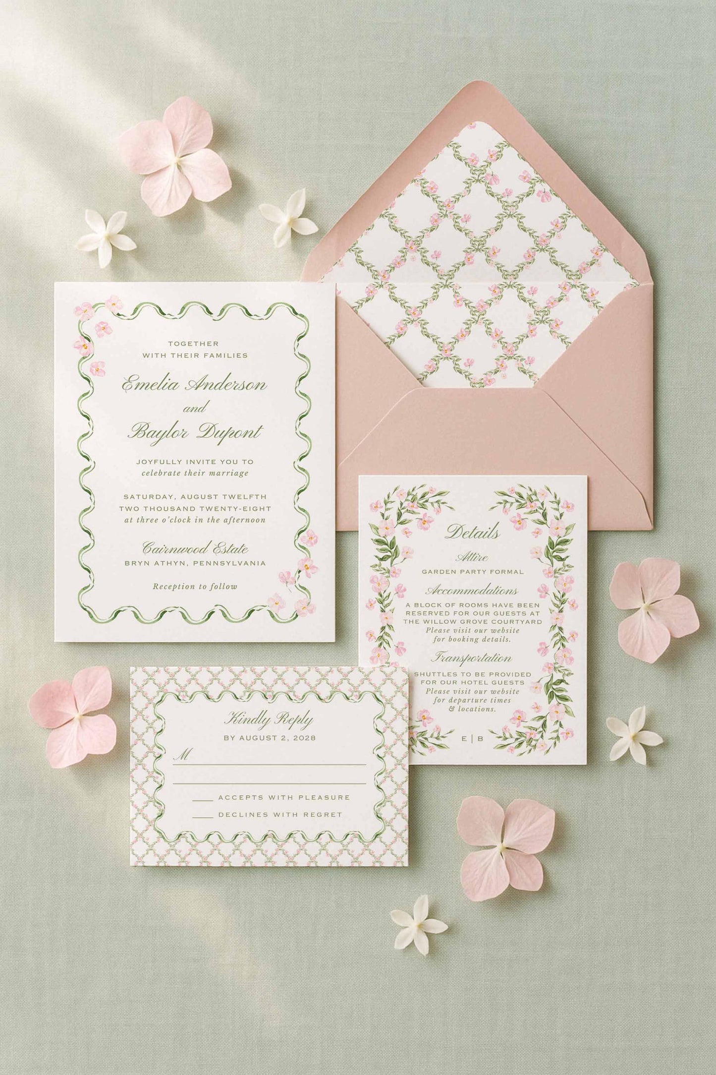 a wedding invitation set against a light green background, with pink flowers scattered around it.