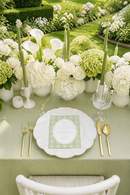 a beautifully set table for a formal dining experience, with a white tablecloth, a white plate, and gold cutlery. The table is adorned with white flowers and candles, creating an elegant and inviting atmosphere.