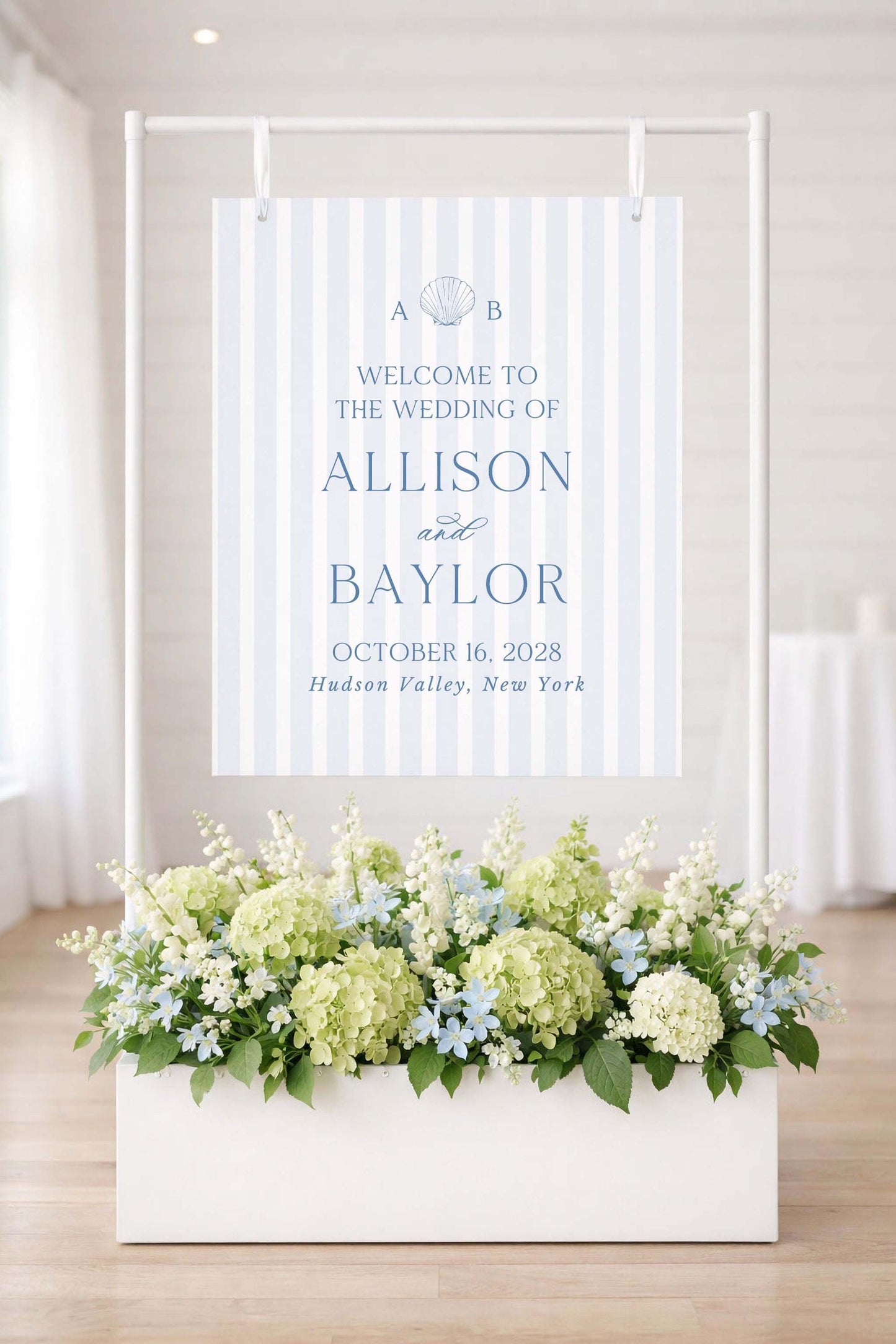 a wedding invitation sign with a floral arrangement in a white planter below it.