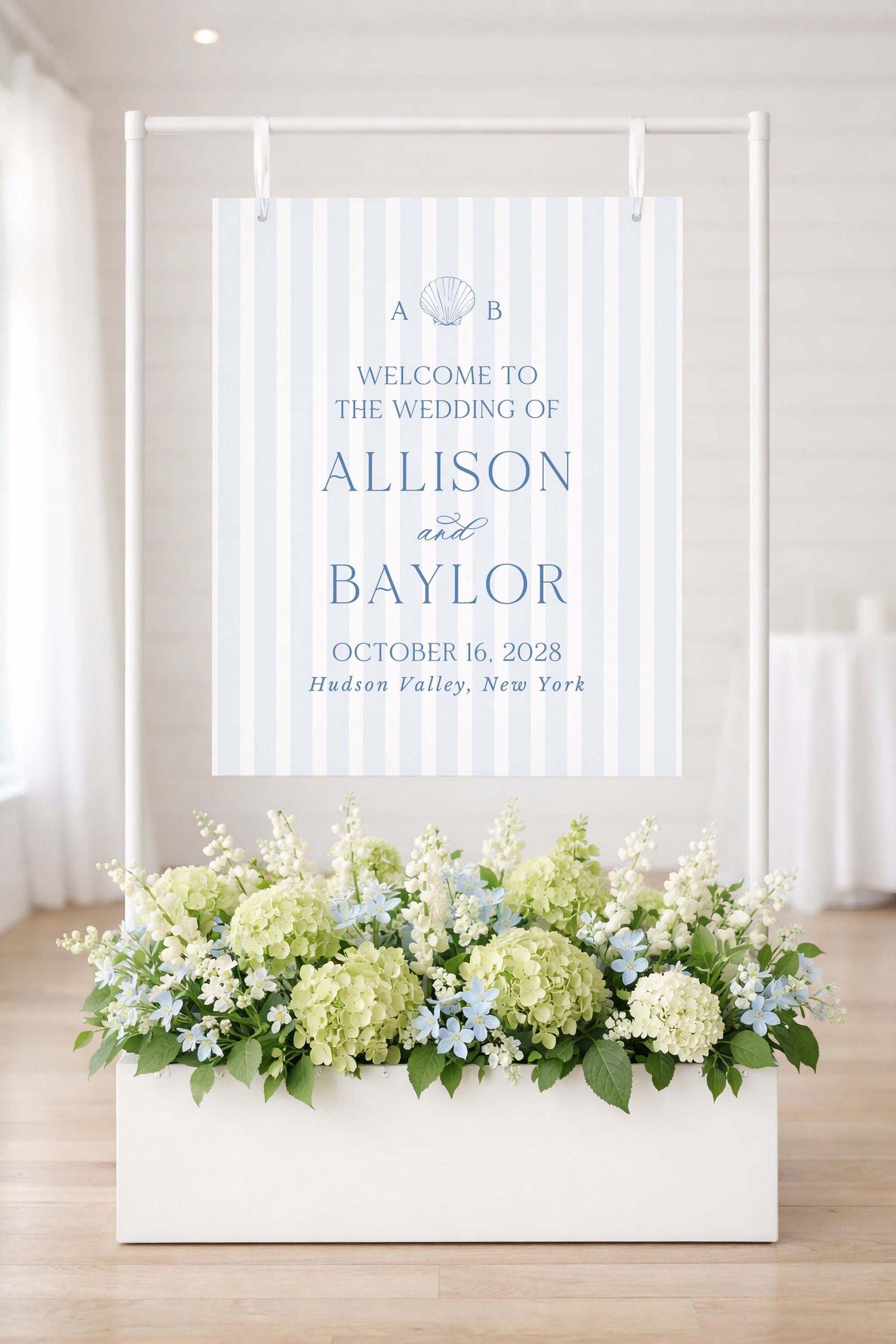 a wedding invitation sign with a floral arrangement in a white planter below it.