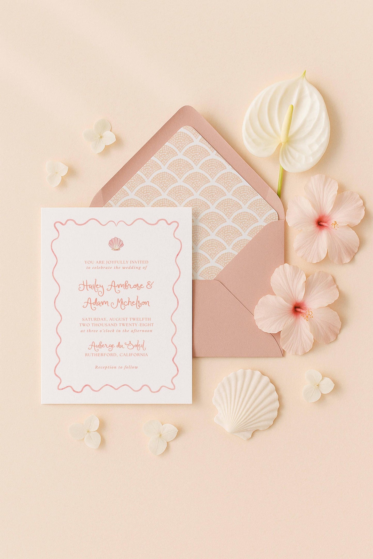 A wedding invitation card with a pink and white color scheme, surrounded by pink and white flowers, shells, and a pink envelope.