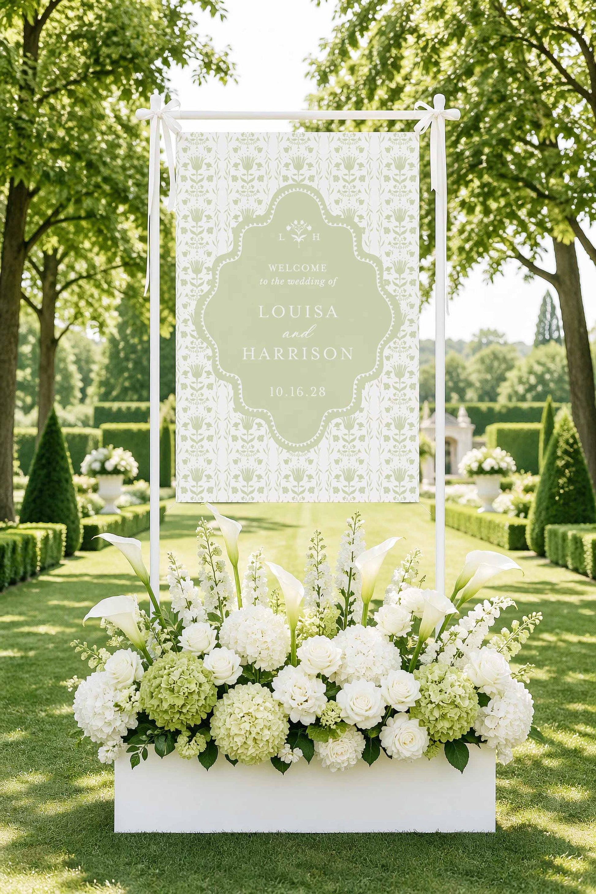 A white banner with floral arrangements in the foreground, set against a backdrop of lush greenery and trees.