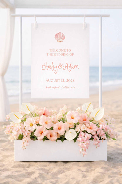 a wedding invitation sign with a beach scene in the background, displaying the names "Haley & Adam" and the date "AUGUST 12, 2028" in a coastal town.
