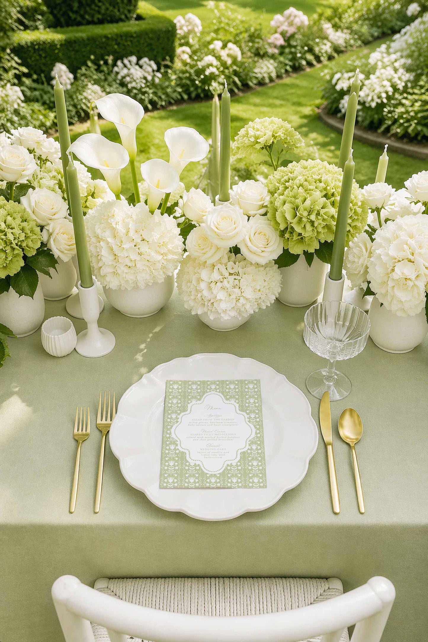 a beautifully set table for a formal dining experience, with a white tablecloth, a white plate, and gold cutlery. The table is adorned with white flowers and candles, creating an elegant and inviting atmosphere.