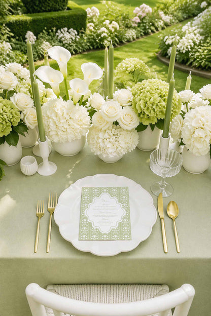 a beautifully set table for a formal dining experience, with a white tablecloth, a white plate, and gold cutlery. The table is adorned with white flowers and candles, creating an elegant and inviting atmosphere.