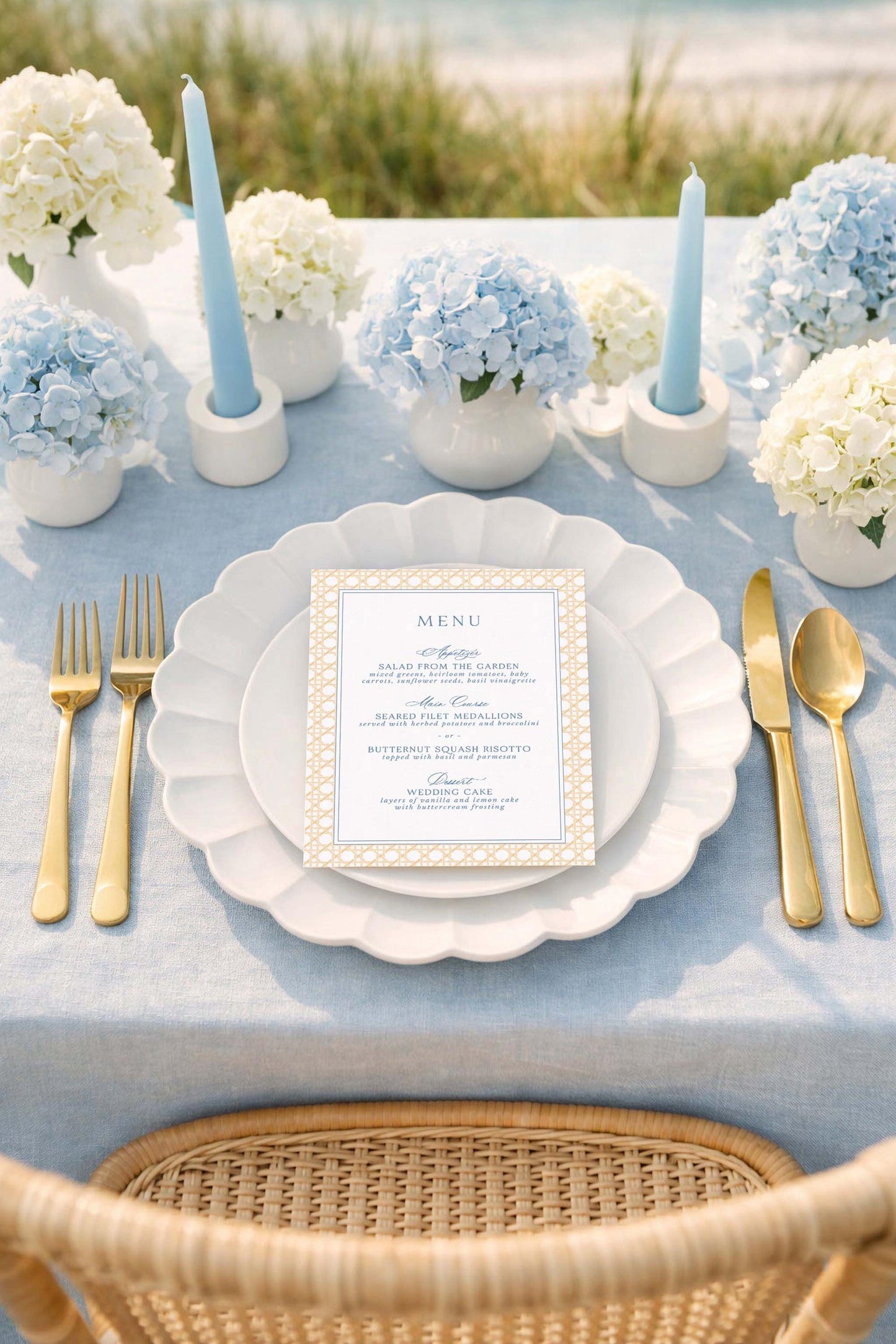 a beautifully set table for a formal dining experience. The table is adorned with a blue and white color scheme, and the centerpiece is a vase filled with blue hydrangeas. The table is set with a white plate, gold cutlery, and a menu card. The overall scene conveys a sense of elegance and sophistication.
