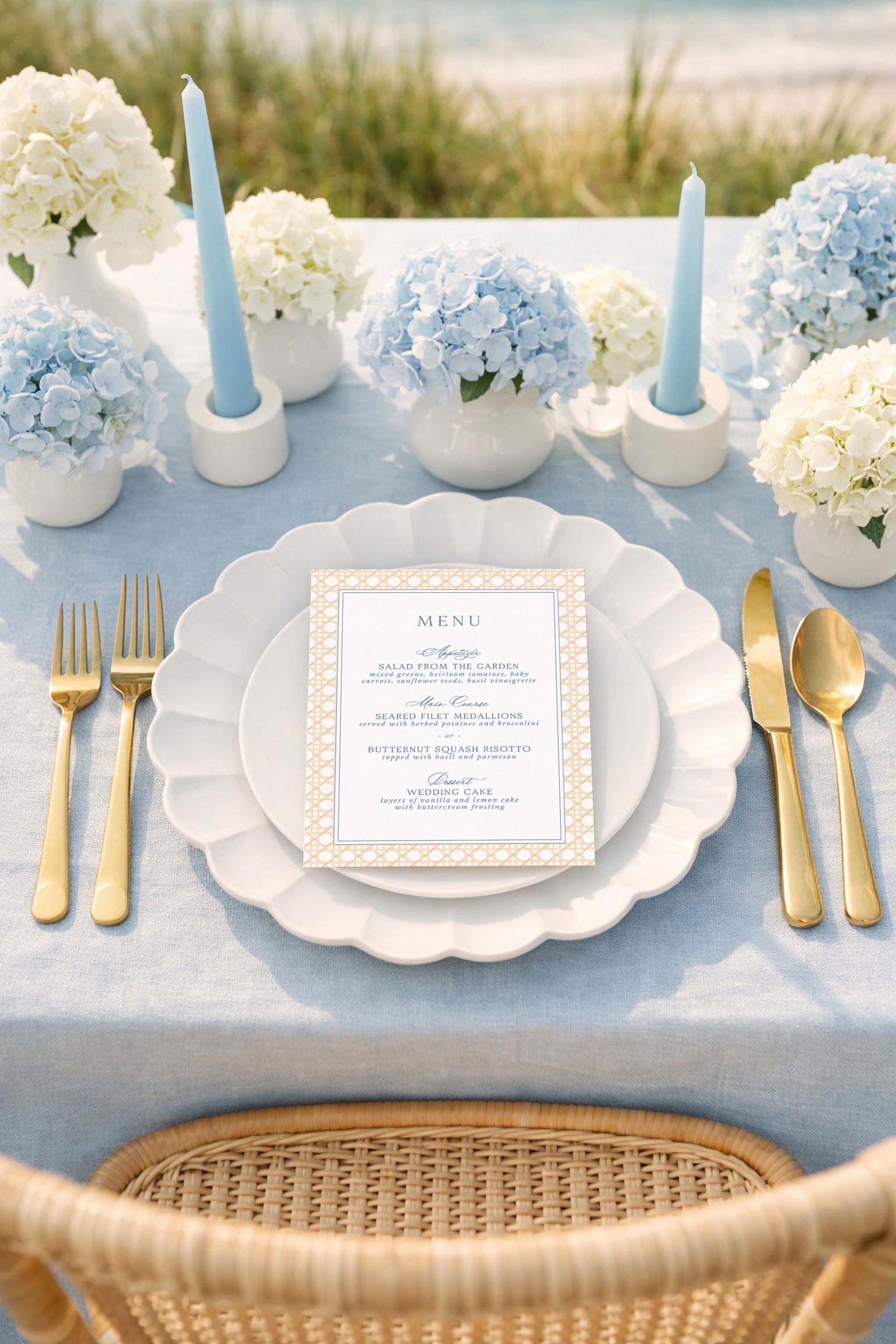 a beautifully set table for a formal dining experience. The table is adorned with a blue and white color scheme, and the centerpiece is a vase filled with blue hydrangeas. The table is set with a white plate, gold cutlery, and a menu card. The overall scene conveys a sense of elegance and sophistication.