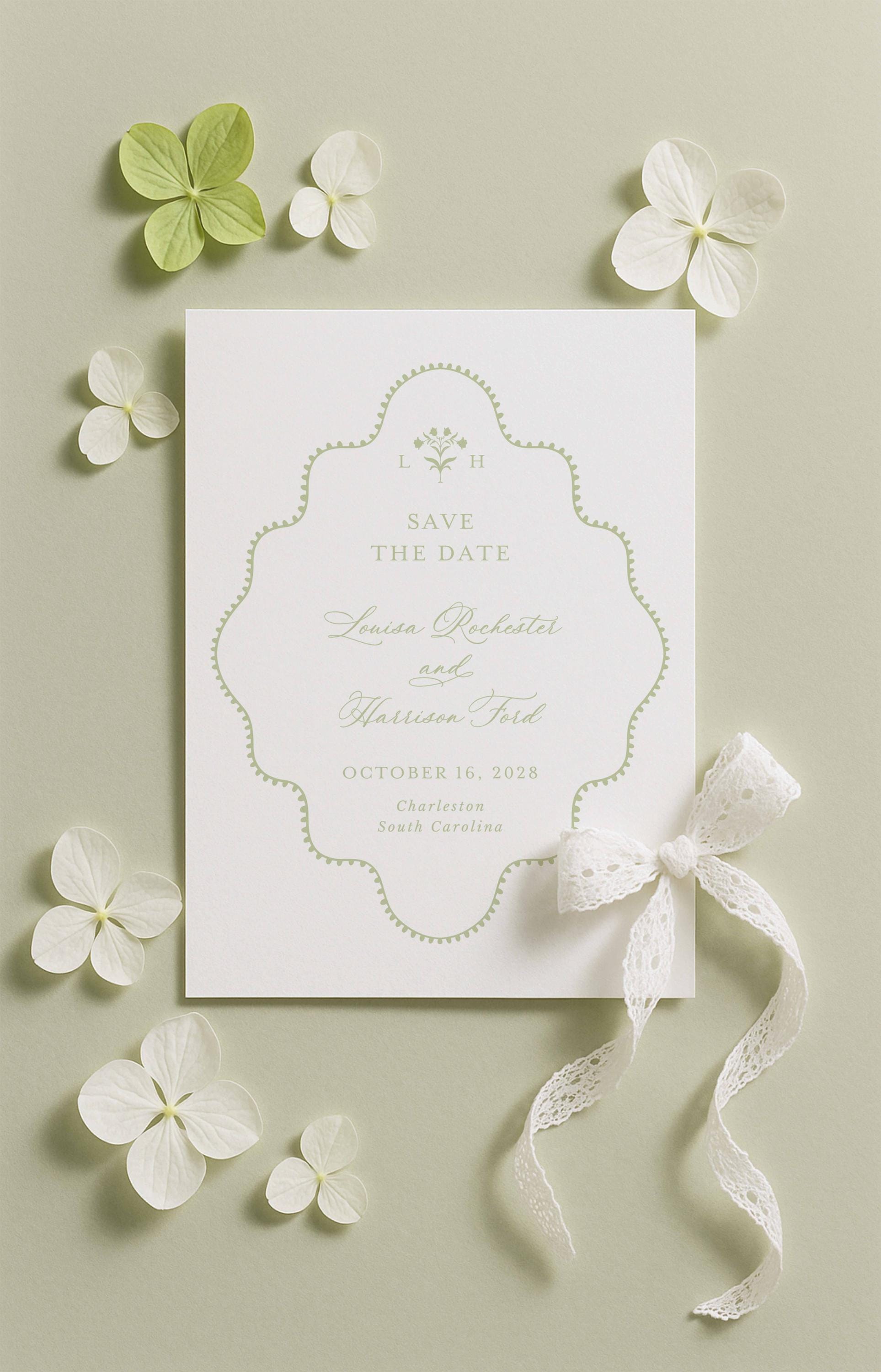 a white wedding invitation card with a scalloped edge, surrounded by white flowers and a white ribbon.