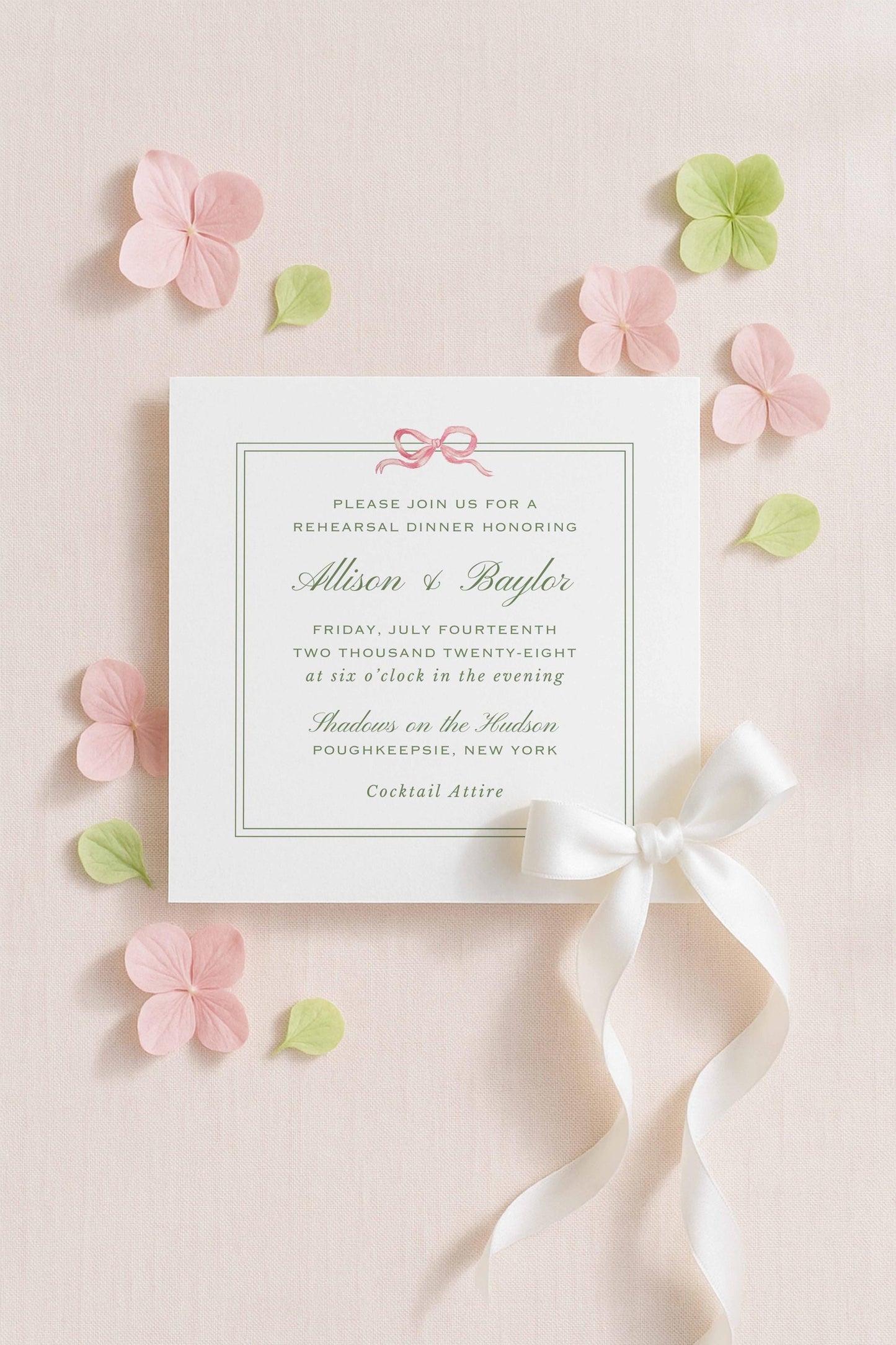 a formal invitation card with a white background, pink and green floral accents, and a white ribbon bow.