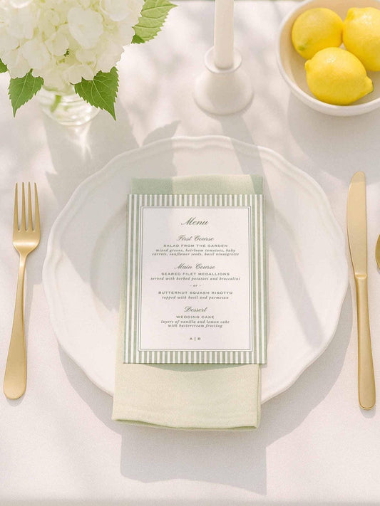 Green striped watercolor wedding menu displayed on a neutral tablescape with lemons and white florals.