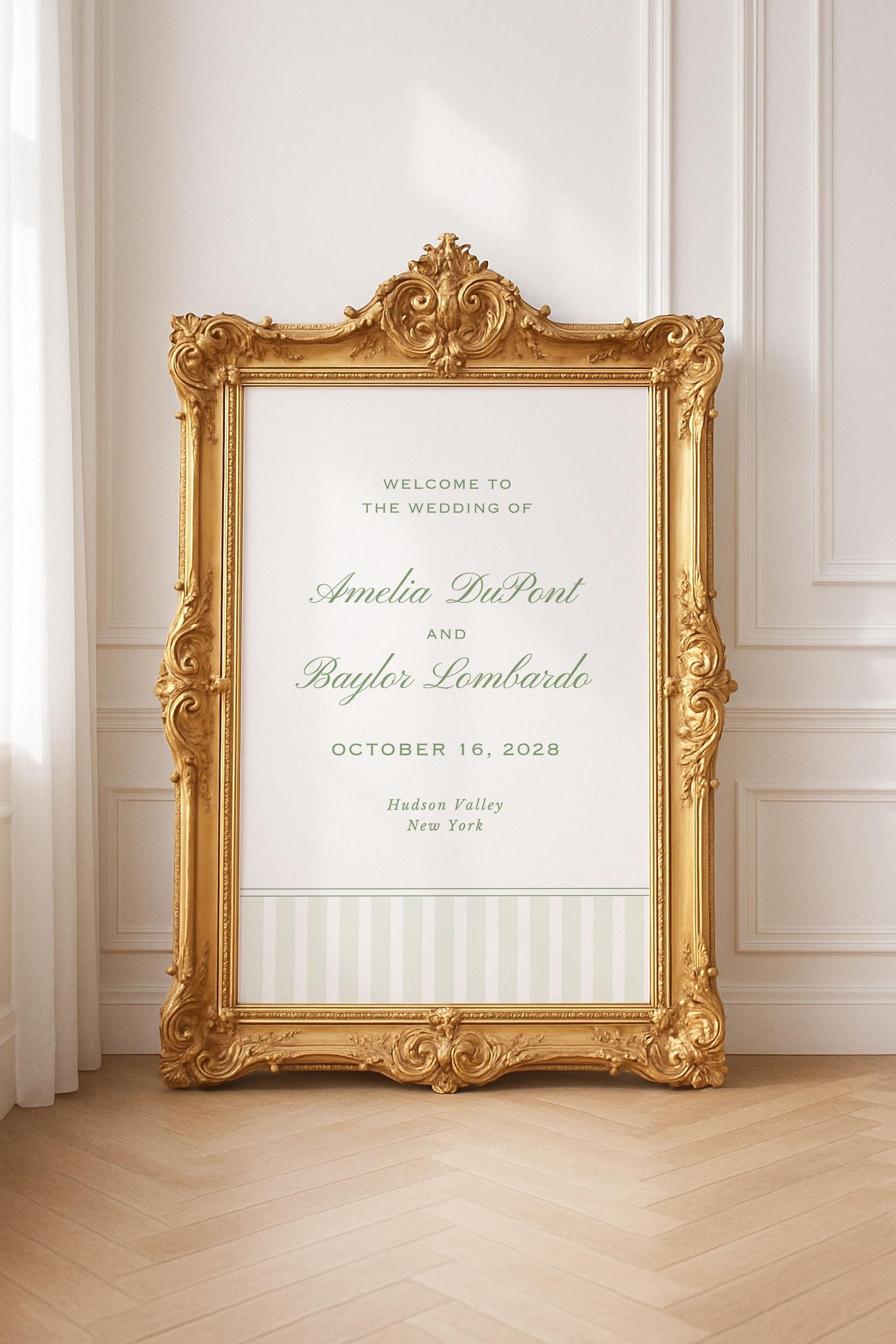 a large, ornate gold frame with a white wedding invitation card inside it, placed on a wooden floor against a white wall.