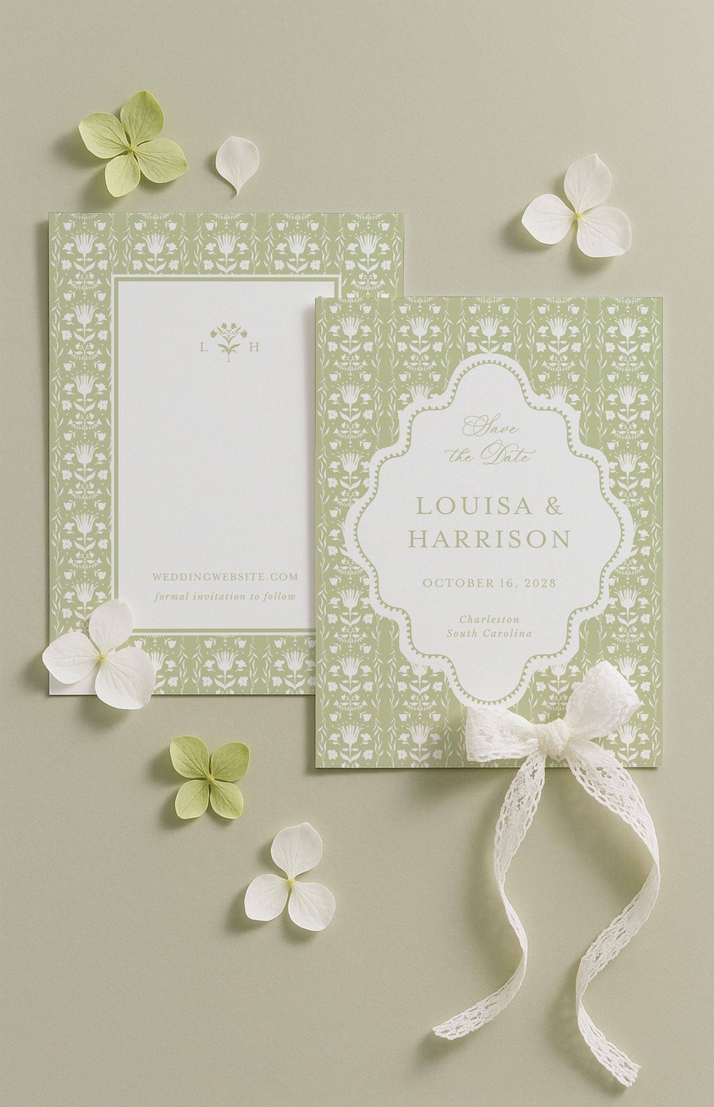 a wedding invitation card with a floral design and a ribbon bow, along with some white flowers and leaves on a light background.