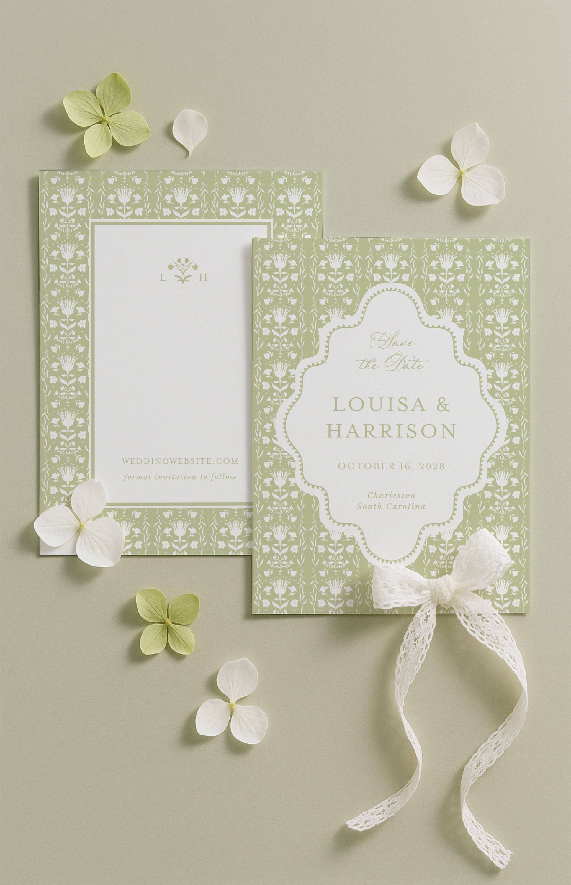 a wedding invitation card with a floral design and a ribbon bow, along with some white flowers and leaves on a light background.