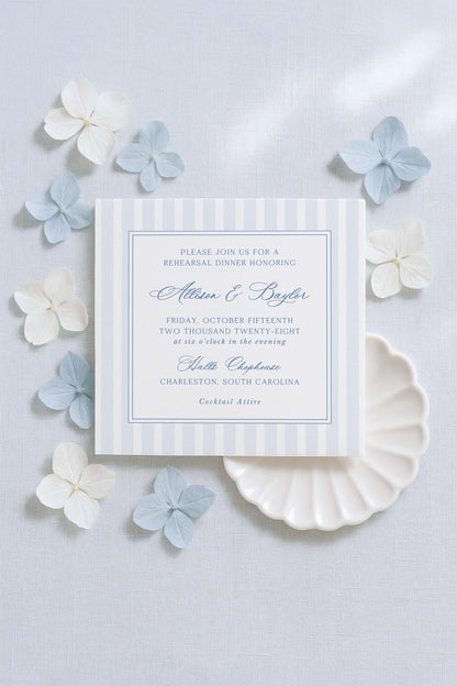 a wedding invitation card with a blue and white color scheme, surrounded by small white and light blue flowers.