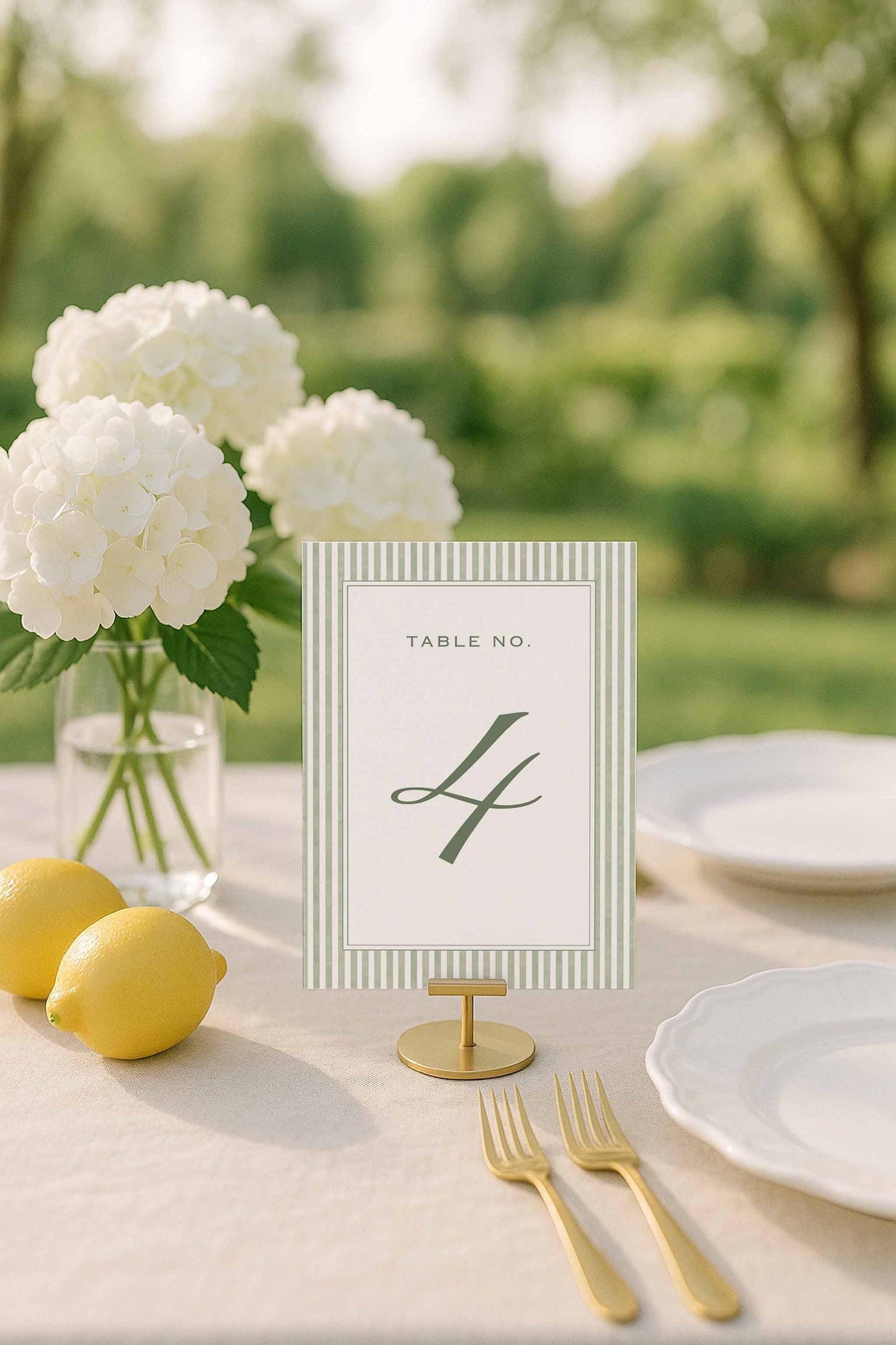 Green striped table number displayed on an elegant tablescape with lemons and white hydrangeas.