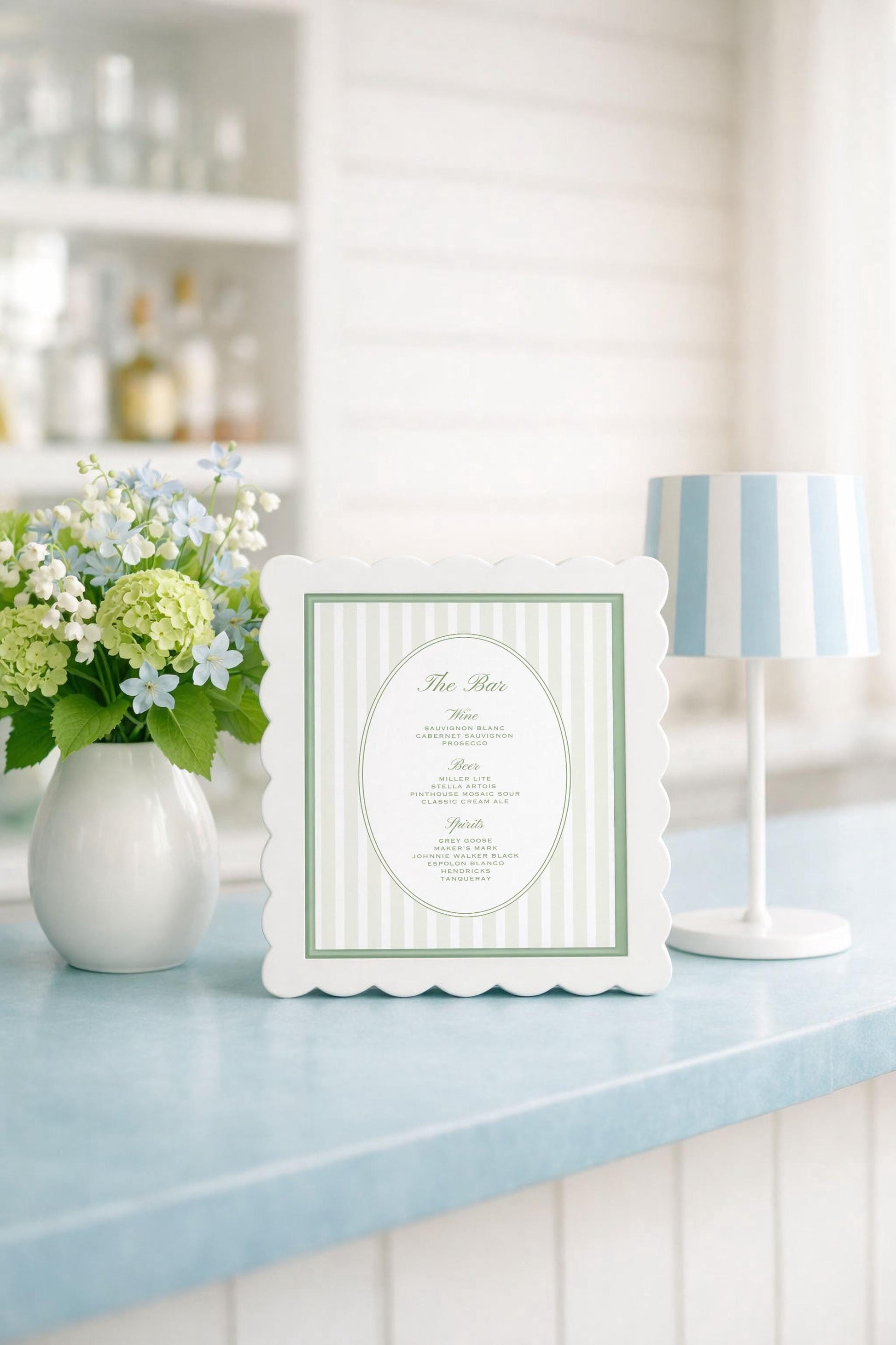 a white framed menu with a green border, placed on a blue countertop next to a vase of white and green flowers.