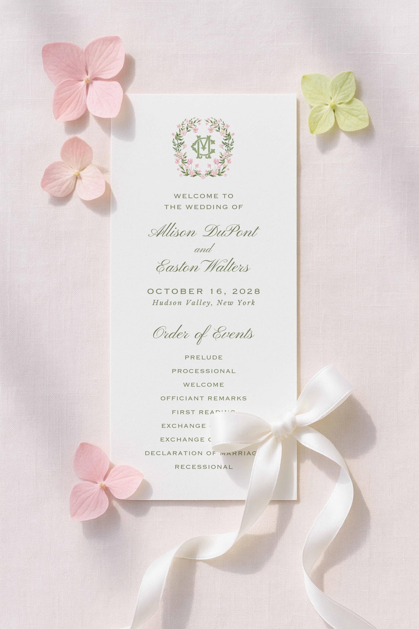 a wedding invitation card with a white background, pink and green flowers, and a white ribbon.