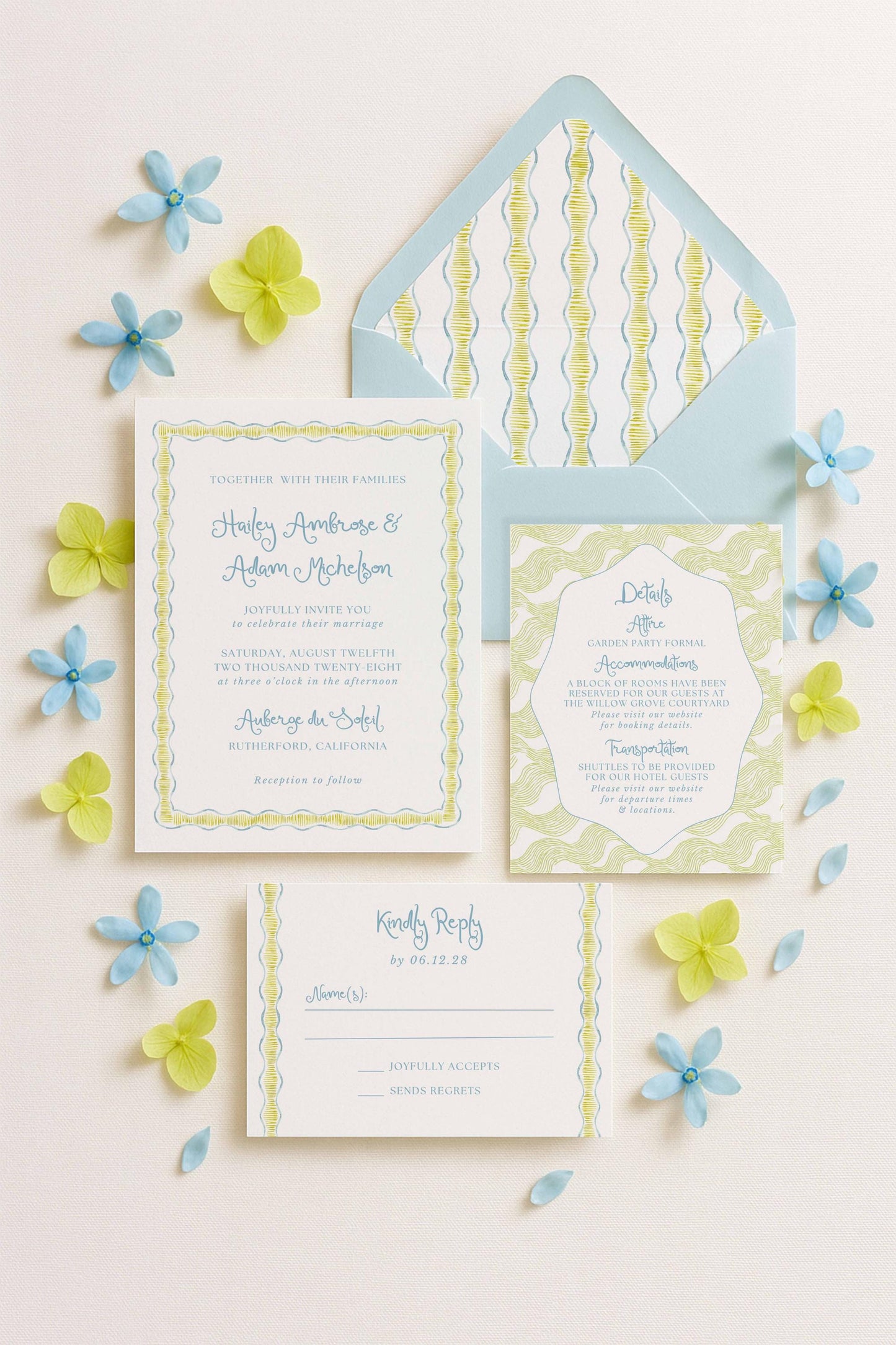 a wedding invitation, an envelope, and a response card, all arranged on a white background with blue and yellow flowers scattered around.