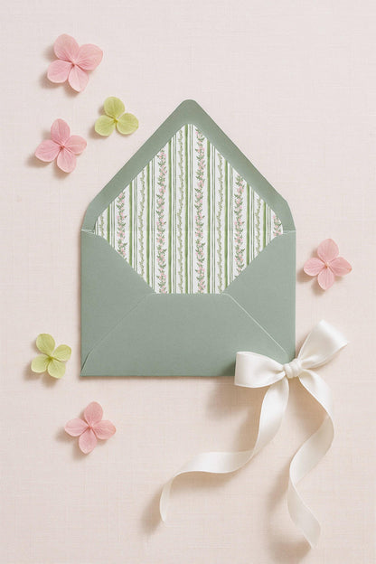 a green envelope with a white ribbon and a bow, surrounded by pink and green flowers on a light pink background.
