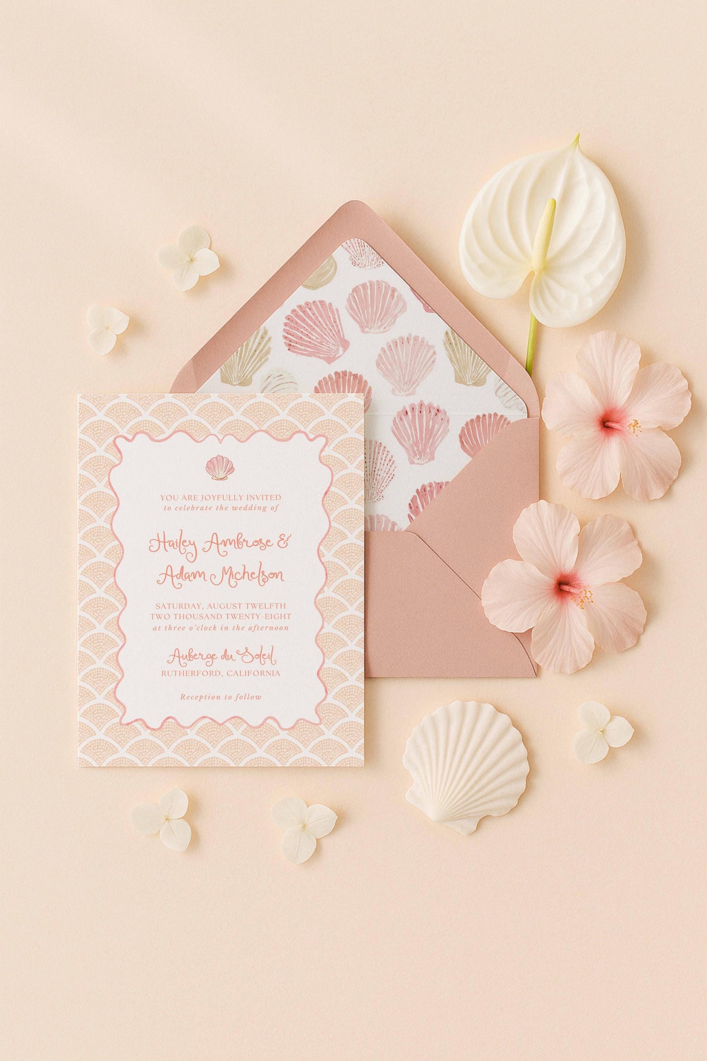 a wedding invitation card with a seashell pattern, surrounded by pink flowers and shells on a peach background.