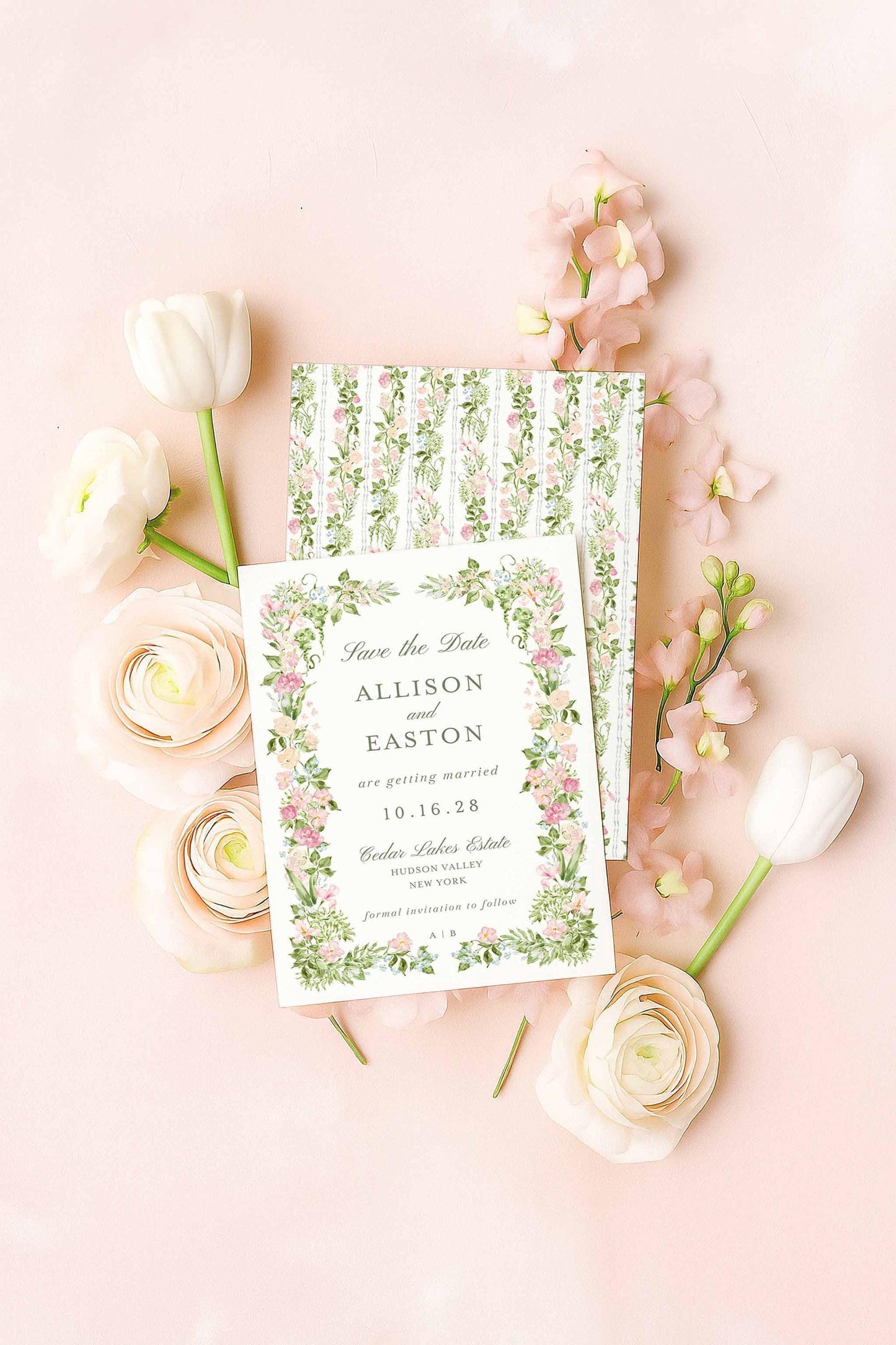 A floral watercolor Save the Date card with matching patterned backer, styled flat-lay on a blush background with ranunculus and tulips.