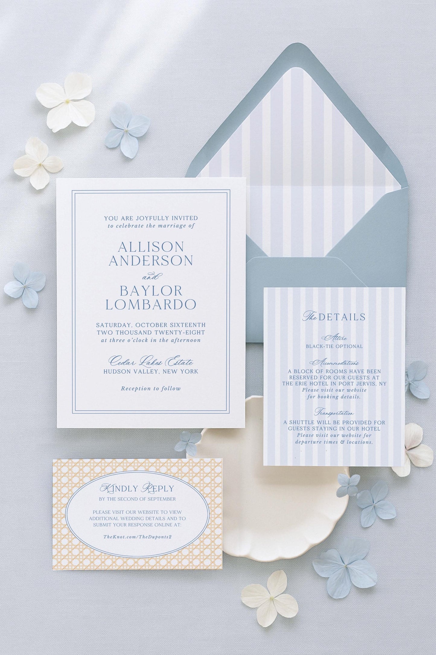 a wedding invitation with a white background and blue and white striped envelope, along with some additional wedding details and a small card.
