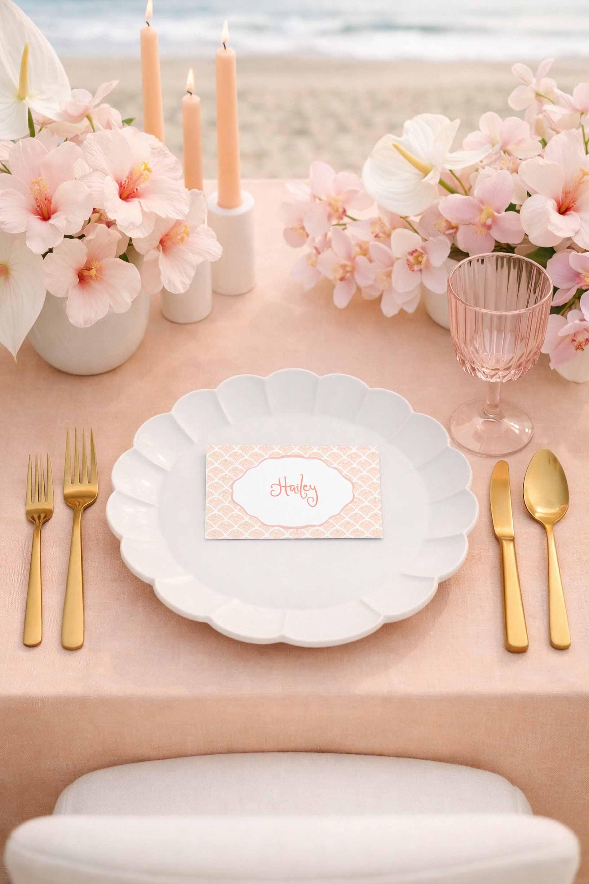 a beautifully set table with a pink tablecloth, a white plate, and gold cutlery. The table is adorned with pink flowers, candles, and a glass of water. The table setting includes a name card with the word "Haley" written on it.