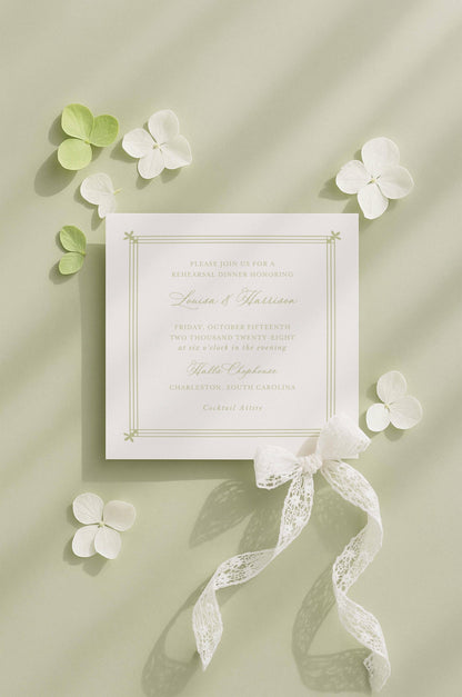 a formal invitation card with a white background and a white ribbon, surrounded by white flowers and leaves on a light green background.
