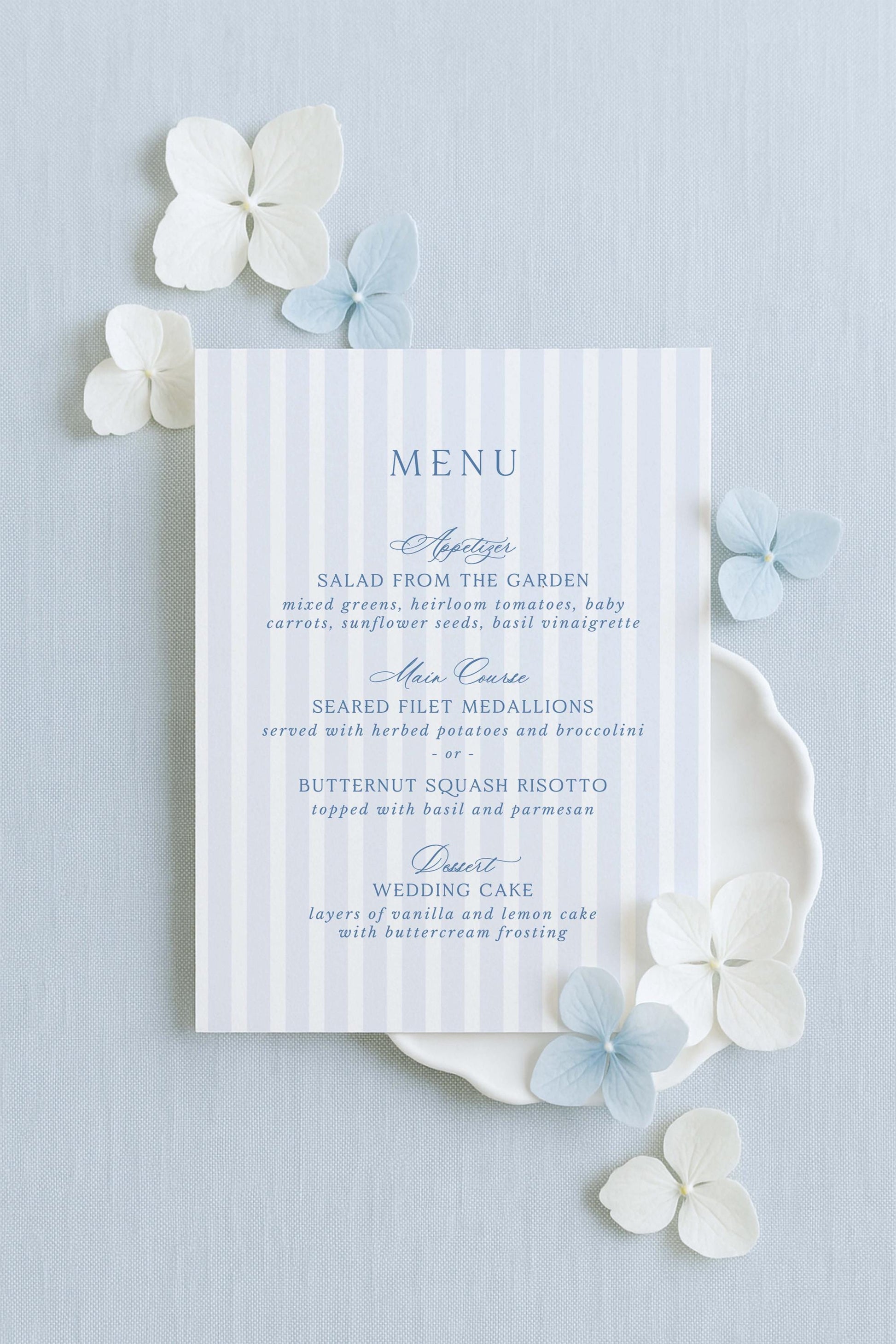 a blue and white striped menu card with a floral arrangement of white and blue flowers surrounding it.
