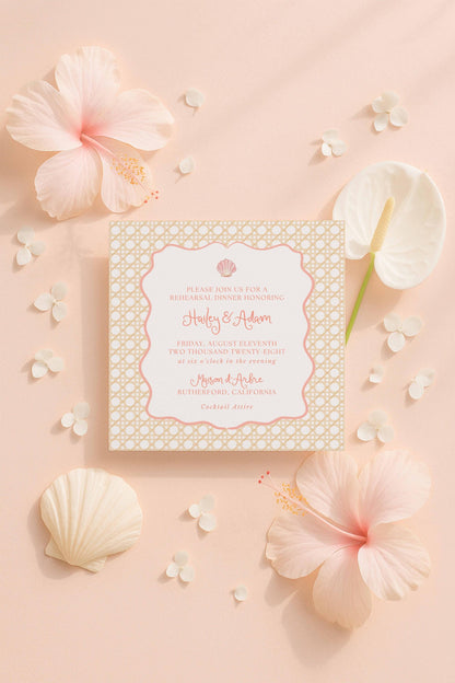 a wedding invitation card with a floral design, surrounded by pink hibiscus flowers, seashells, and other decorative elements on a peach-colored background.