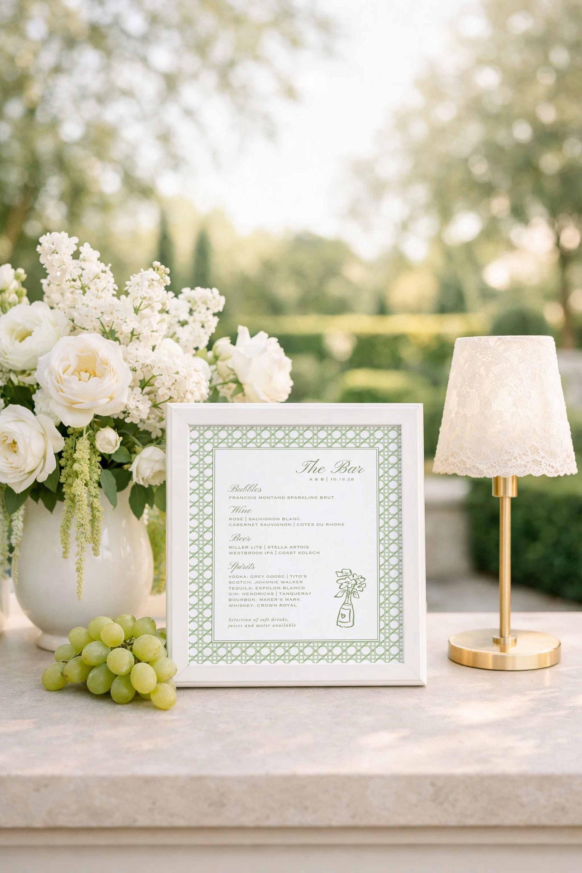 a white framed menu with a green border, placed on a table next to a vase of white flowers and a small lamp.