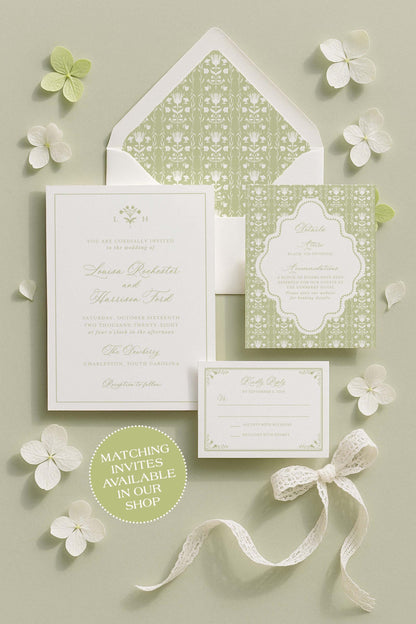 A set of wedding invitations with a matching green and white color scheme, including an envelope, a card, and a small note. The invitations are arranged on a light green background with white flowers scattered around.