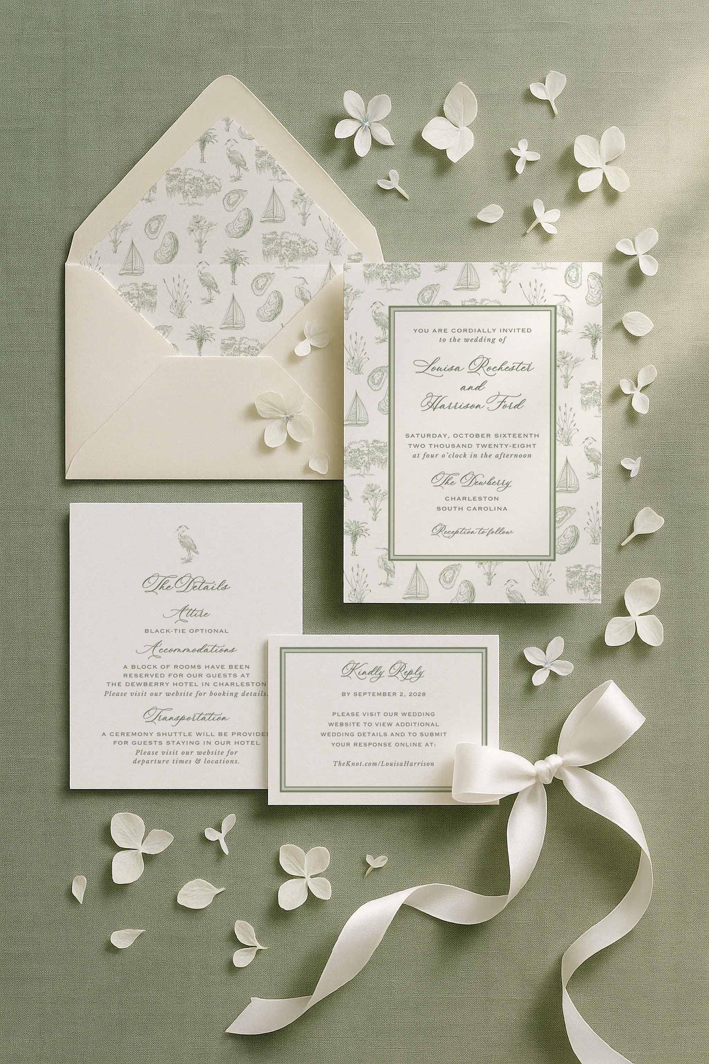 Southern toile wedding invitation suite styled on a sage green linen backdrop with soft white hydrangea petals and a satin ribbon. The invitation features a hand-drawn coastal toile border with palmettos, egrets, oysters, sailboats, oak trees, and marsh grasses. Includes matching details card, RSVP card, and envelope liner with coordinating toile artwork. Fine art southern stationery with soft natural light and elegant styling.